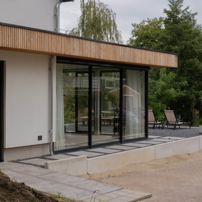 Glazen schuifpui van de uitbouw met houten daklijst, renovatie woning Sleeuwijk