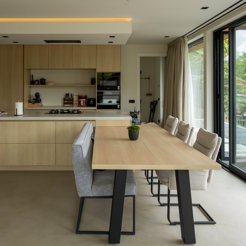 Interieur met lichthouten keuken en lange eettafel in een gerenoveerde woning in Sleeuwijk