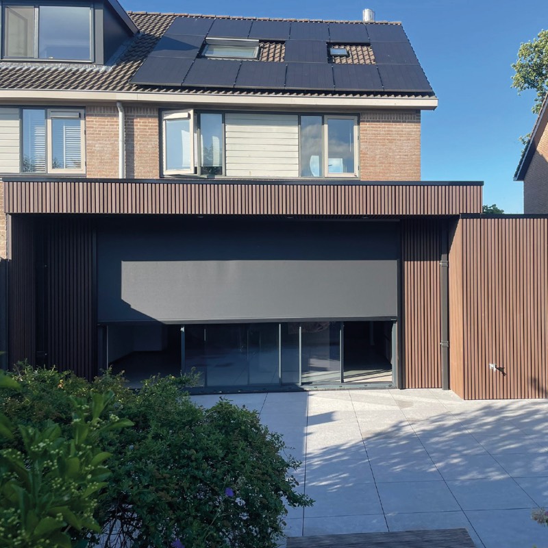 Uitbouw met verticale houten latten en zonnepanelen aan een woning in Rijsenhout